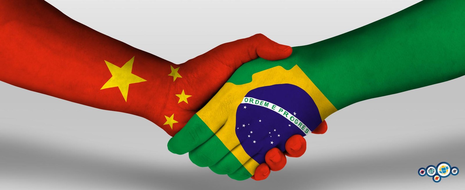Aperto de mãos entre uma mão pintada com a bandeira da China e a outra do Brasil.